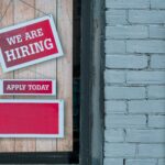An employers window showcasing a now hiring sign to attract immigration talent.