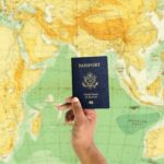 Hand holding a U.S. passport against a world map, symbolizing U.S. citizenship, immigration, global travel, and visa applications.