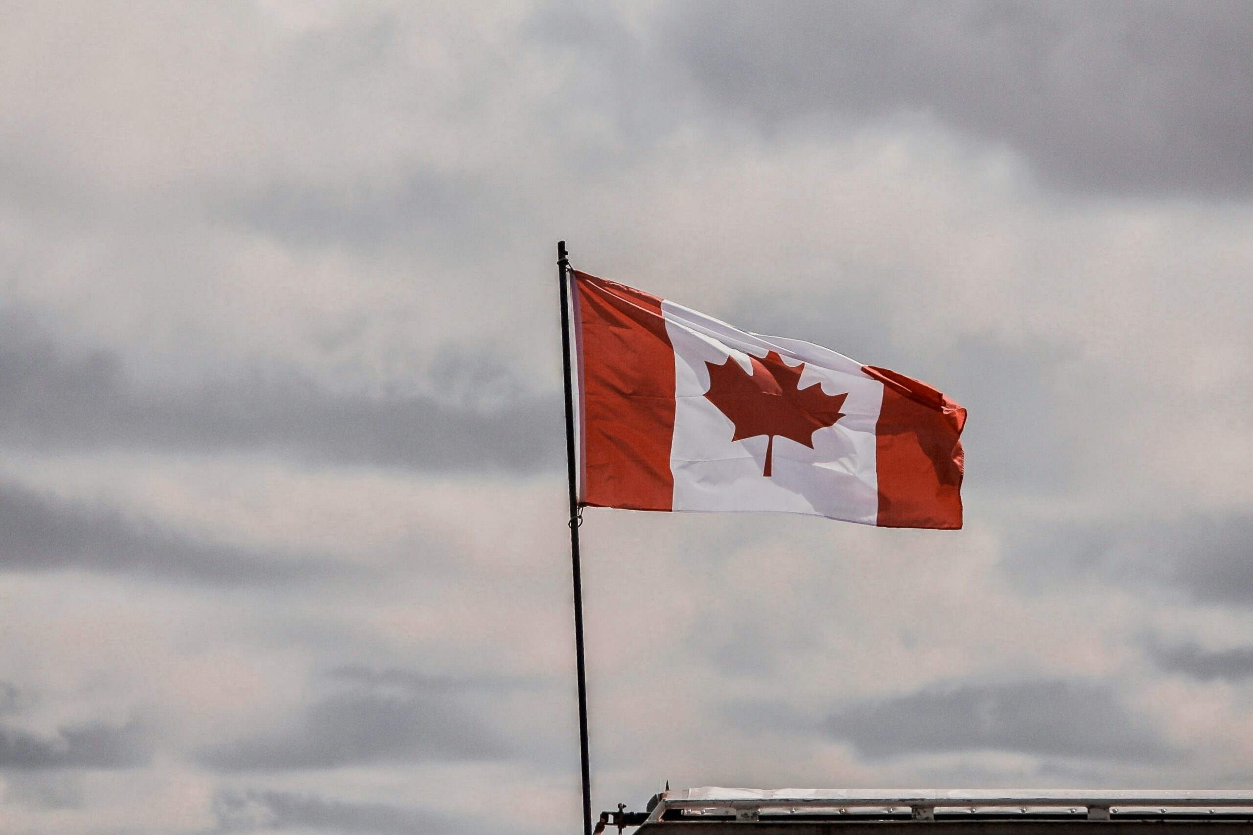 PR Card Renewals - Edwards Law An image showing a big Canada flag blowing in the wind, to represent Canadian Citizenship opportunites.